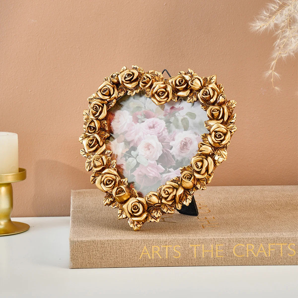 A gold-rimmed heart-shaped frame surrounds a clear resin photo featuring soft pink roses.