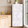 A modern, light gray refrigerator with a white floral decal on the door, set against a wooden cabinet and window.