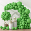 A large archway made of light green latex balloons decorated with white and gold accents.