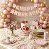 A vintage floral paper party table setting featuring pink and gold plates, cups, and napkins arranged on a table.