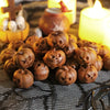 A pile of small, brown resin pumpkins used for Halloween decor, set against a dark mesh background with glowing candles.