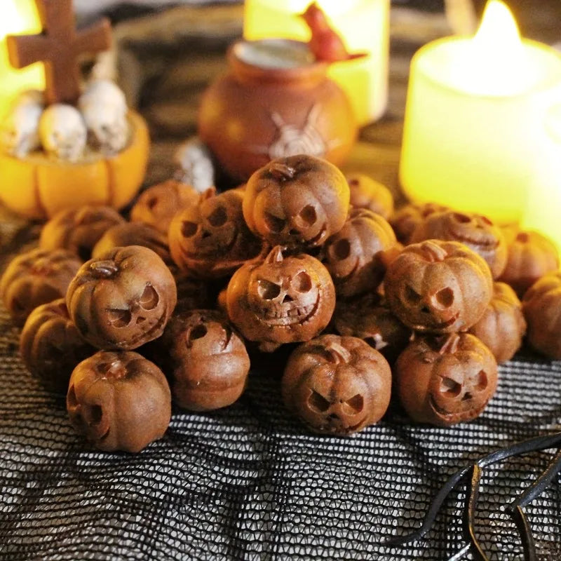 A pile of small, brown resin pumpkins used for Halloween decor, set against a dark mesh background with glowing candles.