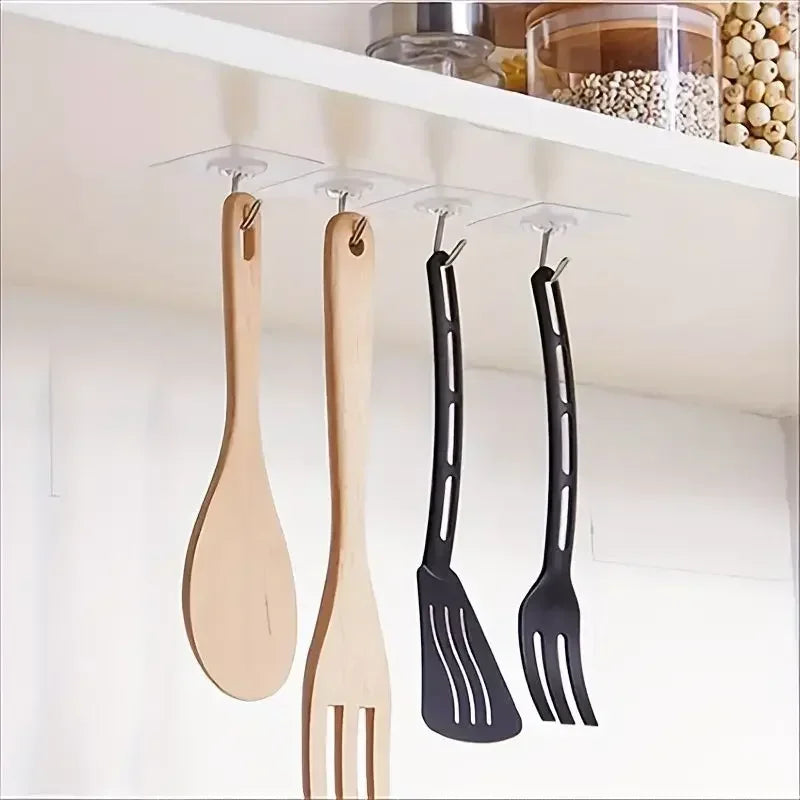 A set of wooden and black silicone spatulas hanging from clear adhesive wall hooks on a white shelf.