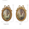 A vintage gold picture frame with a bowknot design, showing two framed paintings.