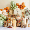 A display of orange and green latex balloons arranged with floral accents for party decor.