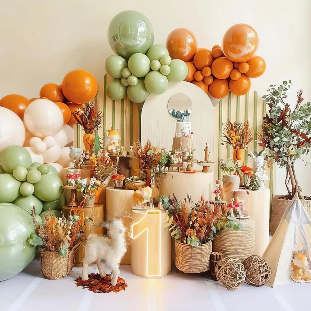 A display of orange and green latex balloons arranged with floral accents for party decor.