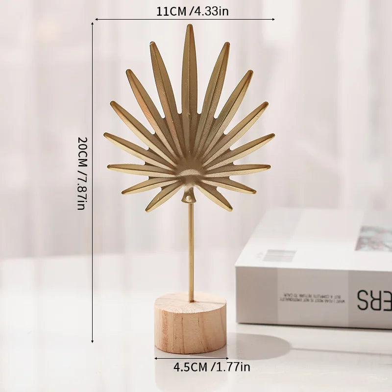 A golden ginkgo leaf ornament set with radiating petals displayed on a wooden base.