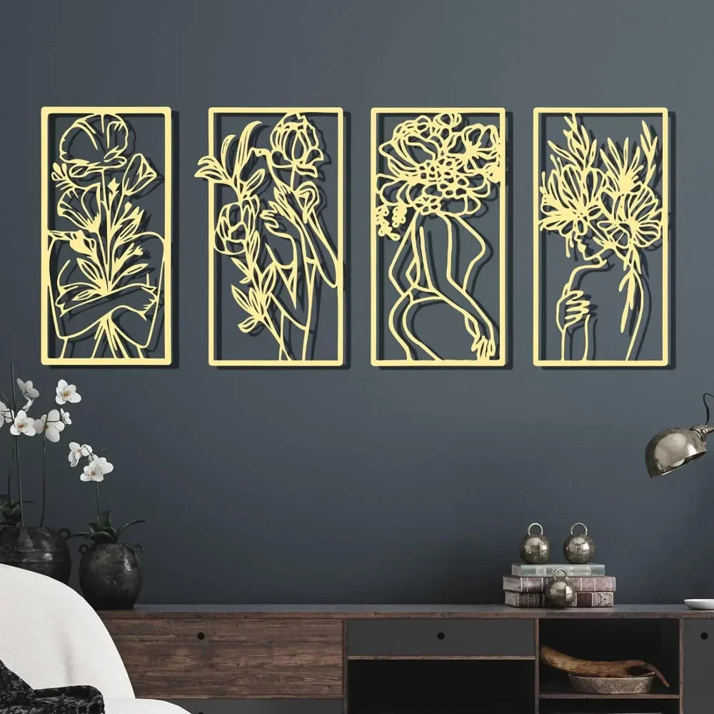 A set of four gold-toned metal wall decor panels featuring abstract female line art silhouettes on a dark gray wall.
