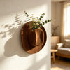 A brown felt cowboy hat with a floral arrangement is mounted on a white wall, casting a shadow.