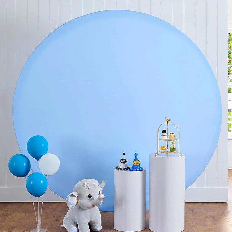 A light blue circular photo backdrop featuring a gray elephant figurine and white cylindrical props.