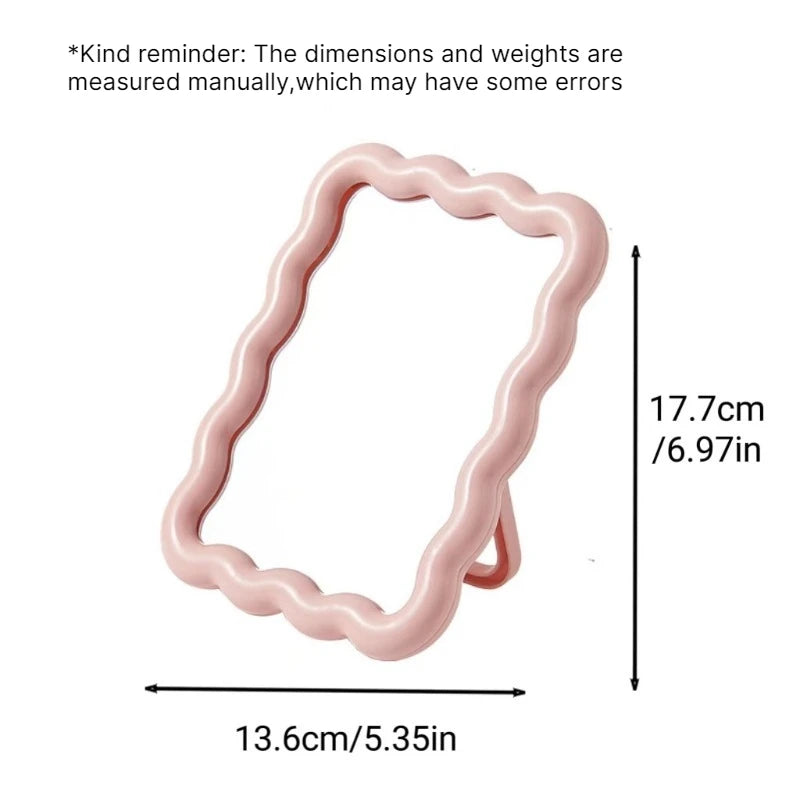 A pink wavy frame makeup mirror with a stand, showing its dimensions.