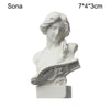 A white plaster bust miniature of a classical Greek figure with flowing hair and drapery.