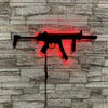 A black gun-shaped light fixture is mounted on a gray stone wall, emitting a bright red glow.