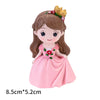 A figurine of a girl with long brown hair wearing a pink dress and a gold crown, used as a princess castle cake topper.