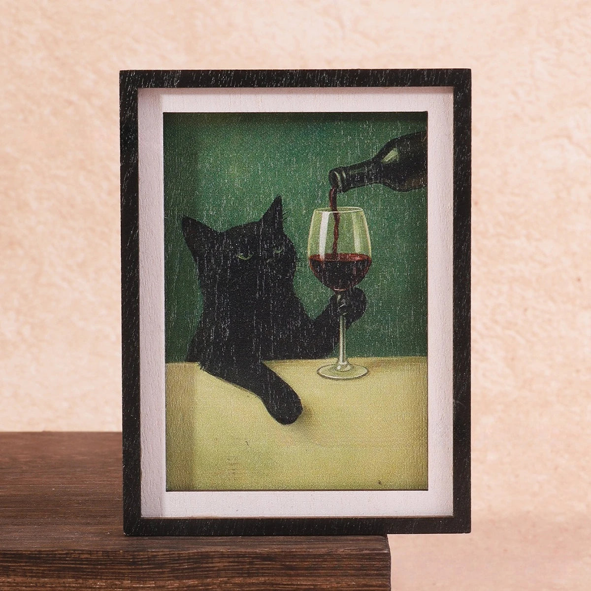 Gerahmtes Bild einer schwarzen Katze, die aus einer Flasche Rotwein trinkt.