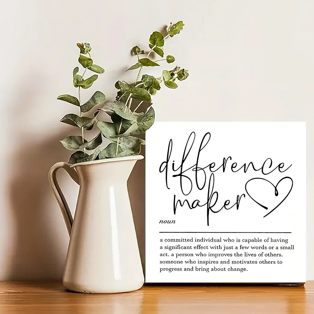A white ceramic pitcher holds green foliage, next to a sign defining a difference maker.