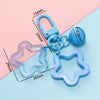 A collection of light blue and pink plastic charm pendants and keychains with various shapes and sizes.