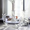 Elegant clear glass pillar candle holders displayed on a white surface next to a lit candle.