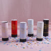 A set of hand twist confetti cannons in white and red colors displayed on a pink surface.
