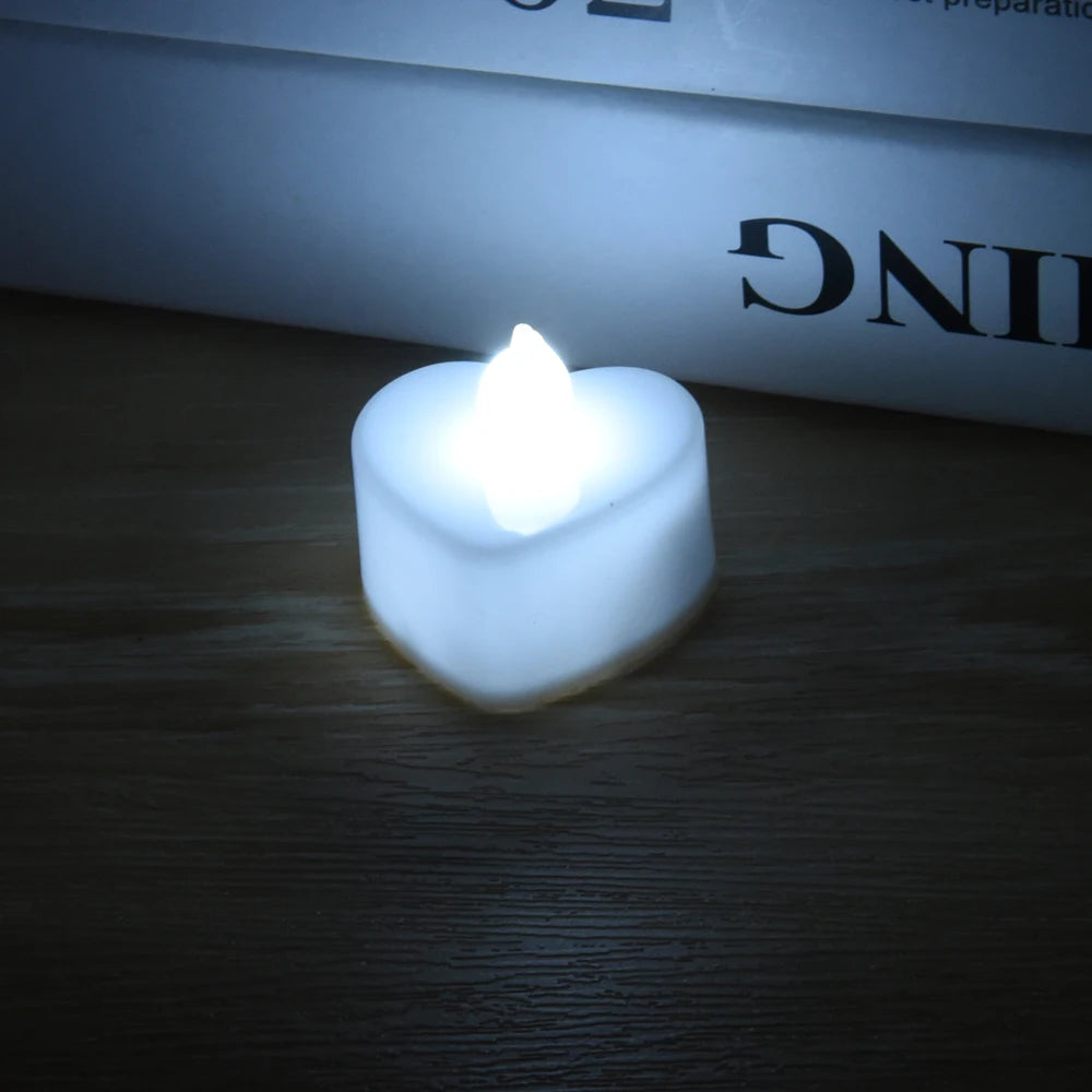 A white, heart-shaped LED tealight candle is lit on a wooden surface.