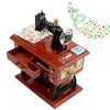 A vintage sewing machine music box with brass accents and decorative ornament on a wooden base.