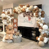 A display of beige and white latex balloons arranged in an archway with a sign that reads Bearly Wait to Meet You