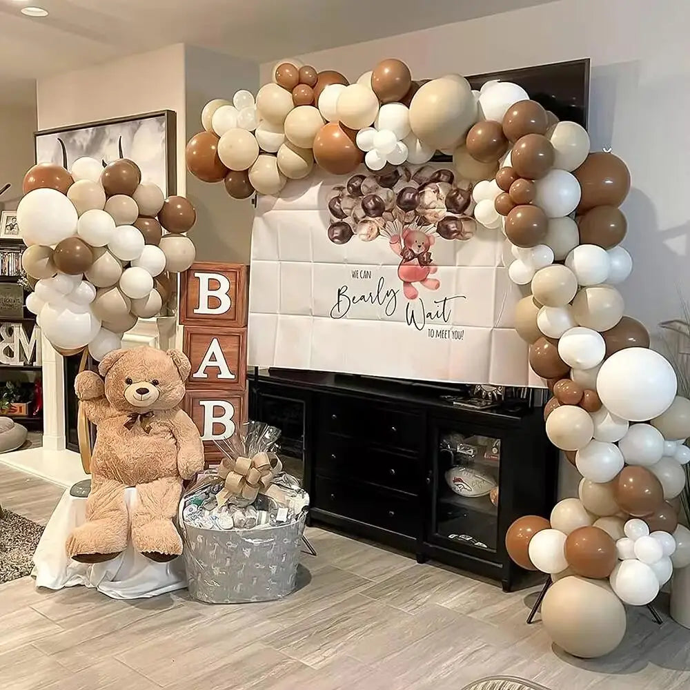 A display of beige and white latex balloons arranged in an archway with a sign that reads Bearly Wait to Meet You