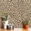 A close-up of a wooden surface featuring a retro leopard print wallpaper, a white pitcher, and a vintage camera.