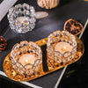 A set of golden crystal candle lantern holders with glowing tea lights and a silver crystal ring.
