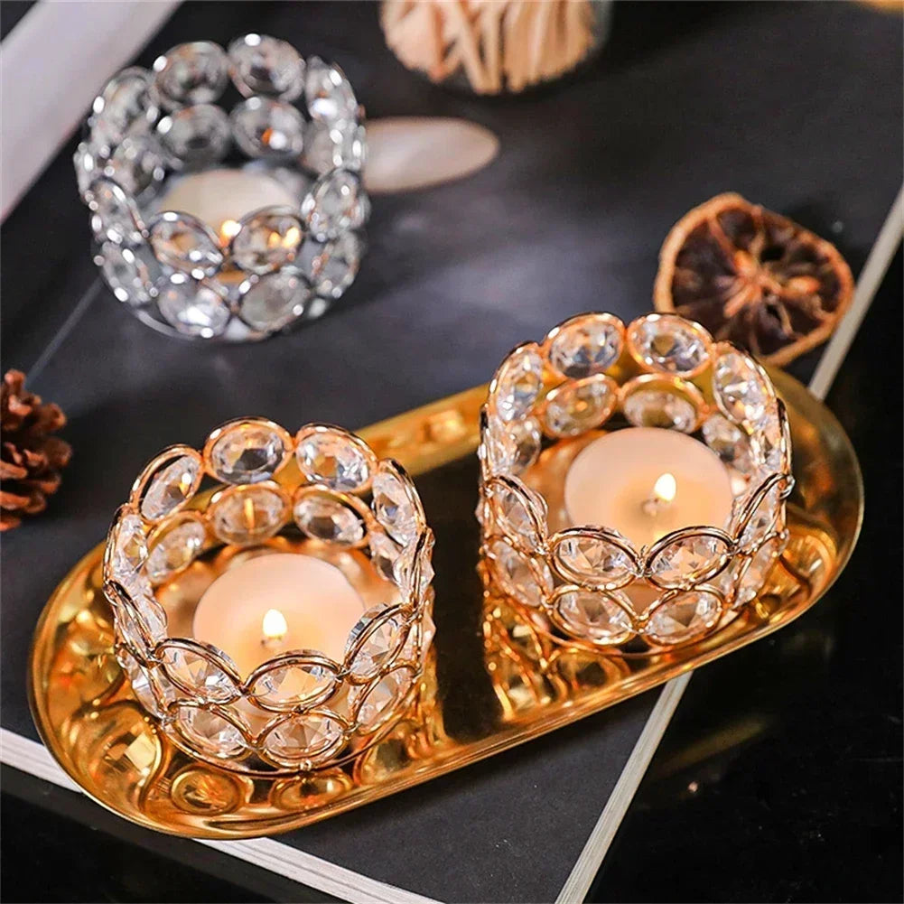 A set of golden crystal candle lantern holders with glowing tea lights and a silver crystal ring.