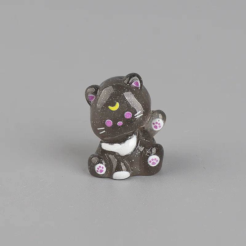 A small, dark gray resin keychain of a cat with pink and yellow markings and white paws.