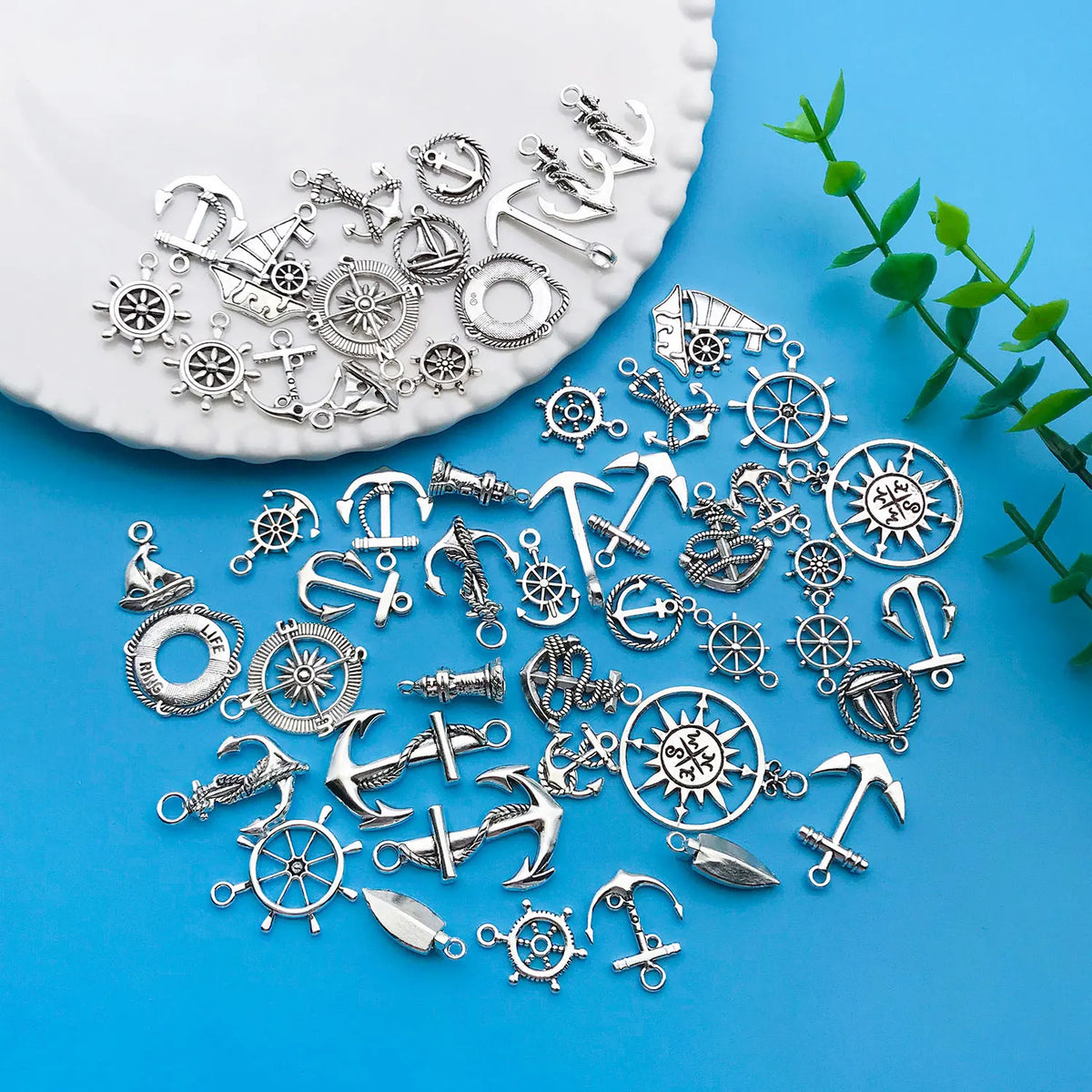 A collection of vintage ship anchor charms and nautical jewelry components scattered on a white plate.