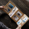 A hand holds a handcrafted accordion photo album displaying various landscape and architectural photographs.