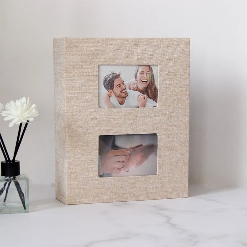 A light beige linen-covered photo album with two framed photos inside.
