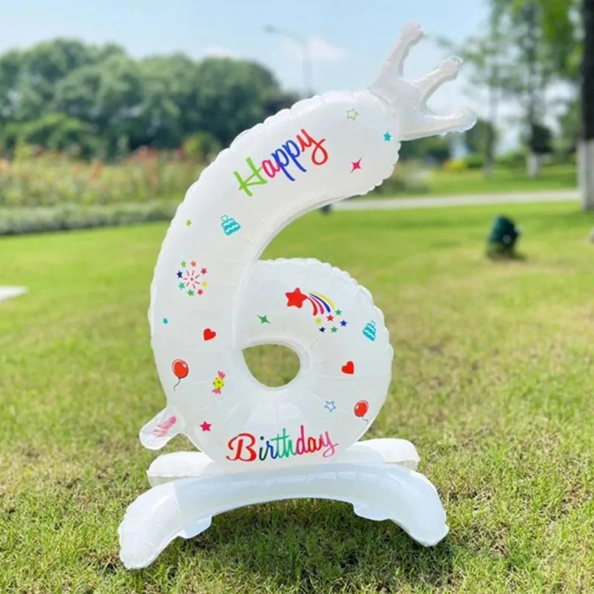 A white foil balloon shaped like the number 6 with a crown and birthday text standing on a base.