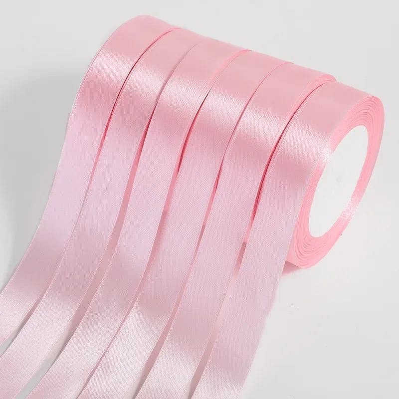 Pink silk satin ribbons rolled and stacked, showing a smooth texture and vibrant color.