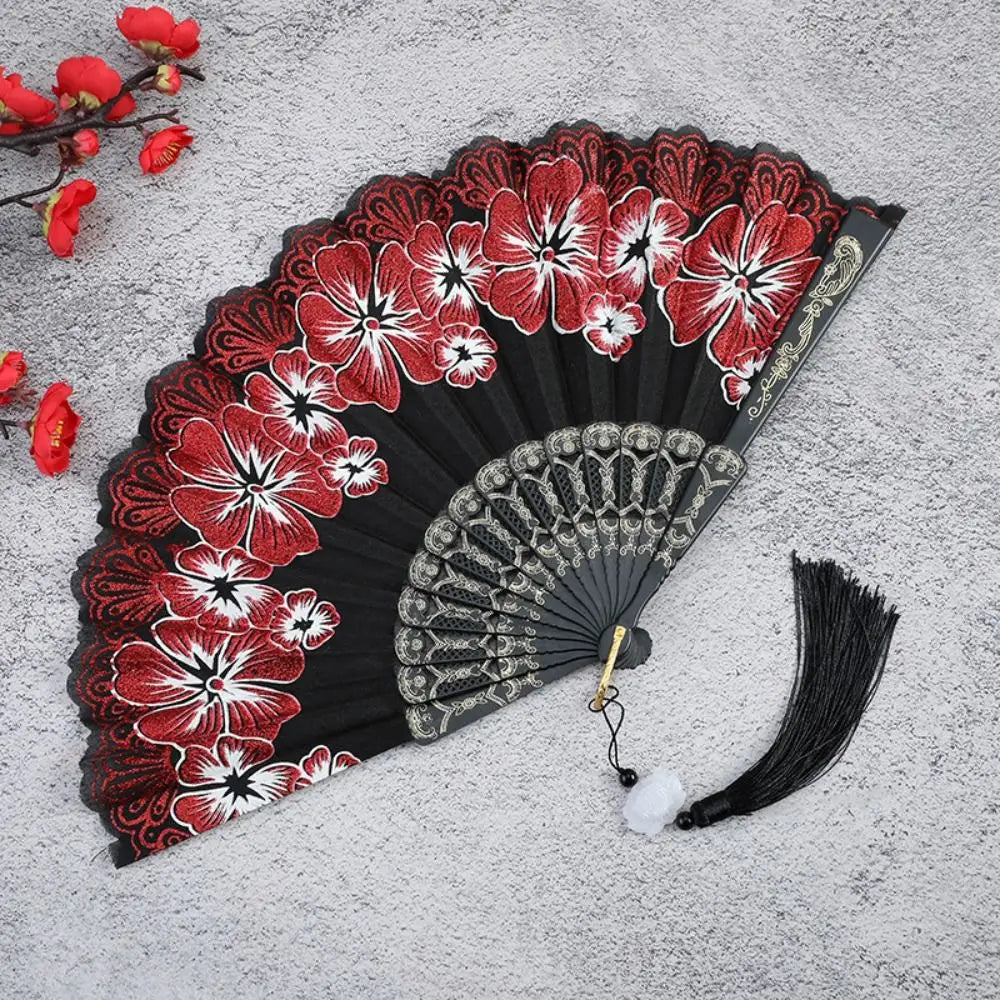 A black folding fan decorated with red and white floral patterns on a gray background.