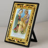 A framed Catholic Holy Family icon featuring Jesus, Mary, Joseph, and an archangel, displayed in a black and gold ornate fram