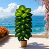 A vibrant green artificial palm tree with 24 large leaves potted on a patio overlooking the ocean.