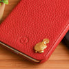 A red leather wallet features a gold tortoise figurine as a decorative element.