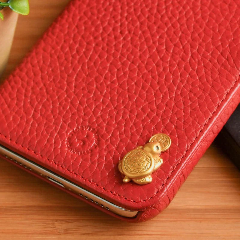 A red leather wallet features a gold tortoise figurine as a decorative element.