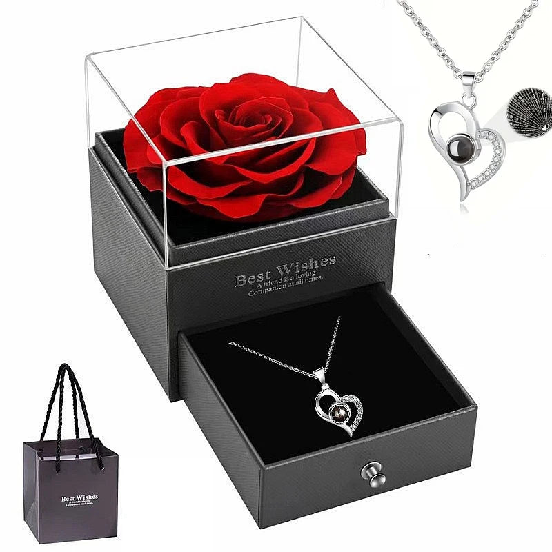 Silbernes herzförmiges Rosenhalskette in einer schwarzen Geschenkbox mit einer frischen roten Rose.