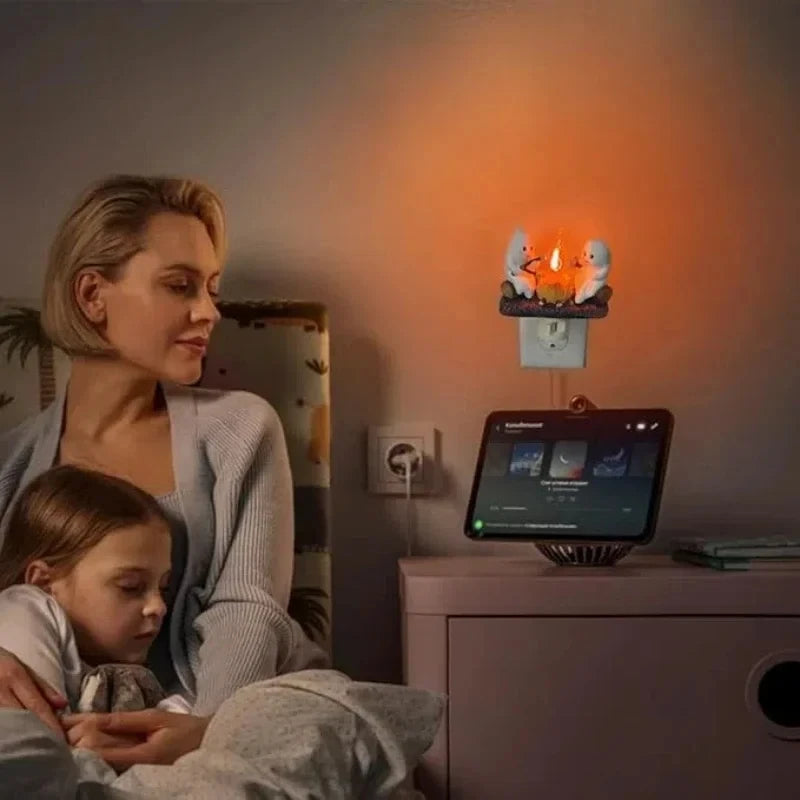 A woman is sitting next to a child in a dimly lit room, observing a Ghost Bonfire Flickering Night Light on a shelf.