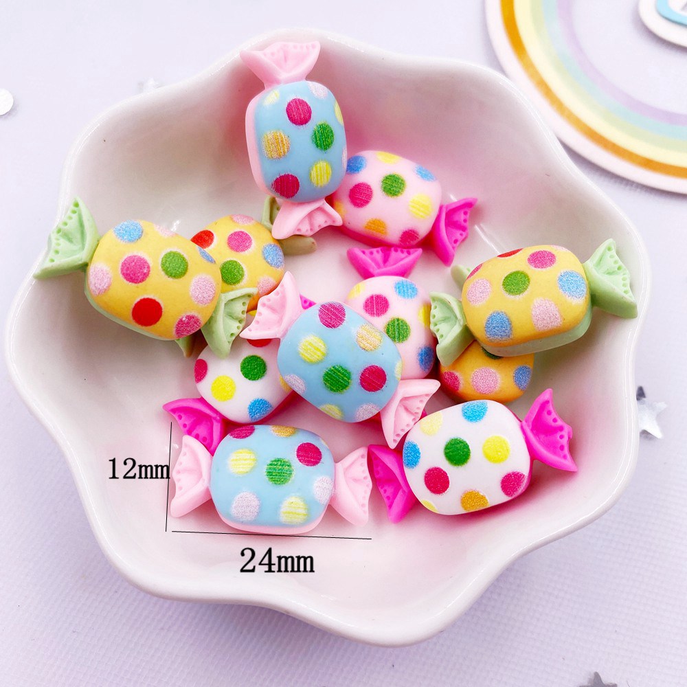 A collection of colorful, oval resin candy cabochons in pink, yellow, and blue with gold speckles arranged in a white dish.