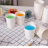 A collection of white disposable paper cups filled with various colored drinks on a checkered napkin.