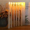 A row of white taper candles with lit flames stands in front of a light-colored display box.