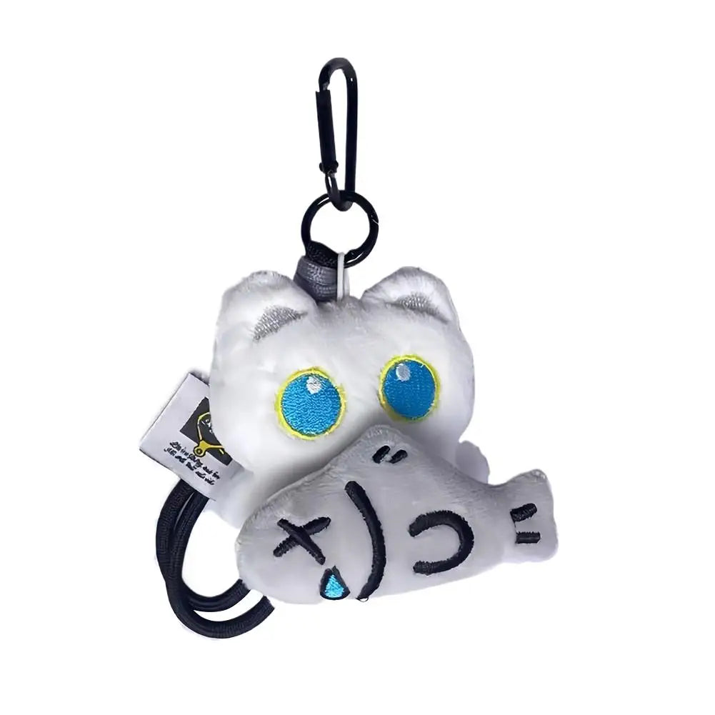 A white seal plush keychain with blue eyes and black markings hanging from a black loop.