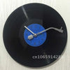 A close-up view of a black vinyl record with a blue clock face and hands.