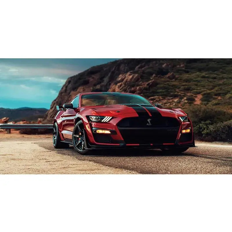 A red Ford Mustang Shelby GT parked on a dirt road with mountains in the background.