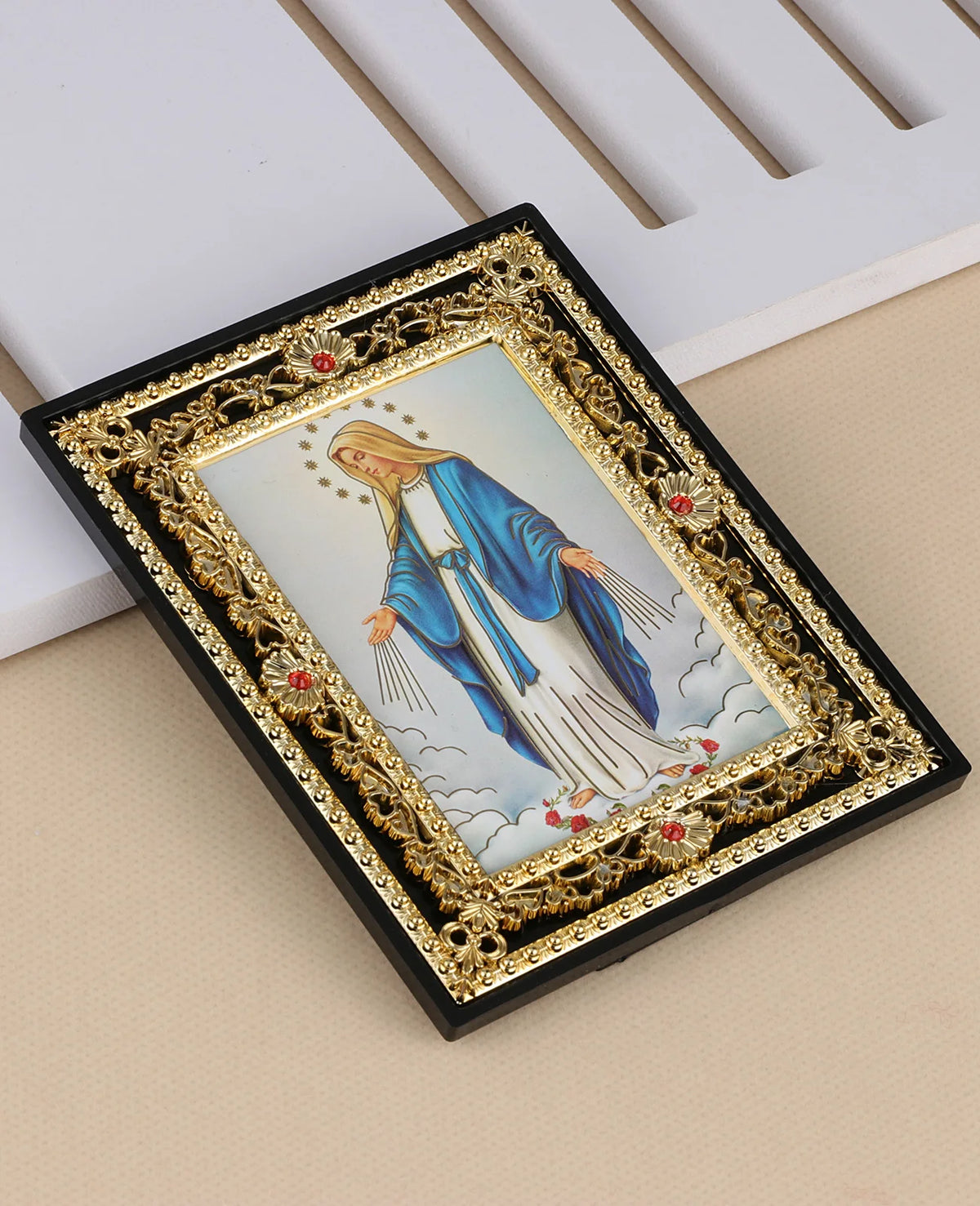 A framed Catholic icon depicting the Archangel St. Michael in blue and white robes with a golden ornate frame.